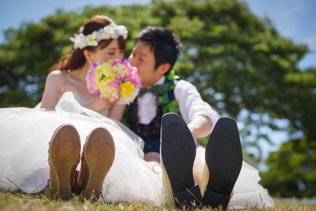 アラモアナビーチにあるマジックアイランド。芝生に座った可愛らしい2人を映したウェディングフォト 。